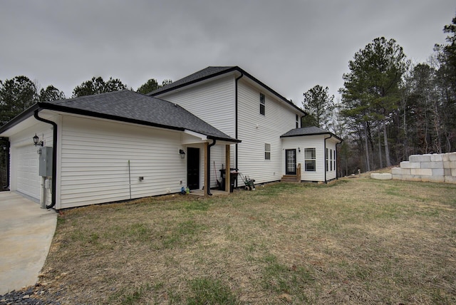 rear view of property featuring a garage and a yard