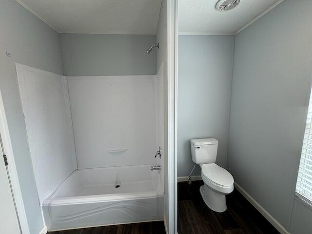 bathroom featuring wood finished floors, toilet, shower / bathtub combination, baseboards, and visible vents