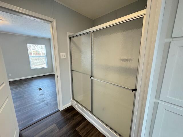 bathroom featuring a shower with shower door, wood finished floors, and baseboards