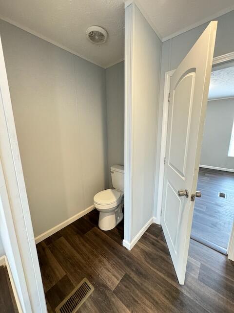 bathroom with toilet, visible vents, wood finished floors, and baseboards