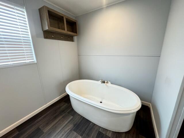 bathroom with a soaking tub, wood finished floors, and baseboards