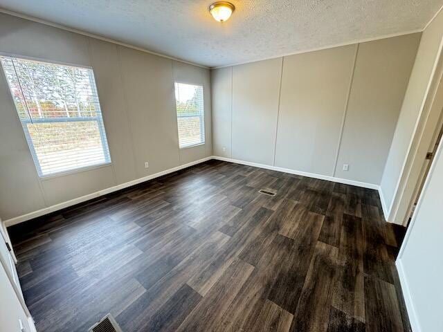 unfurnished room with baseboards, a textured ceiling, dark wood-type flooring, and a decorative wall