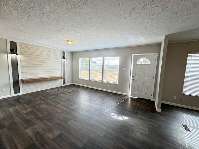 entrance foyer featuring baseboards, visible vents, wood finished floors, and a textured ceiling