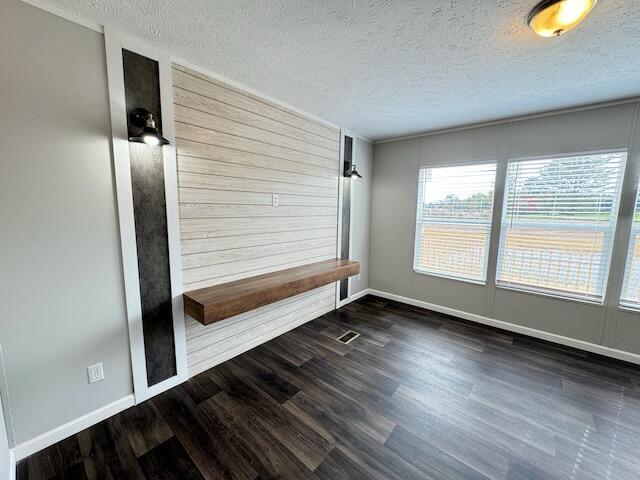 interior space featuring a textured ceiling, dark wood-style flooring, and baseboards