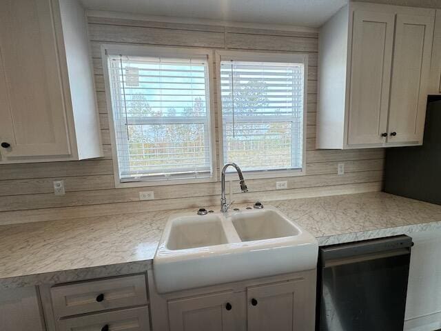 kitchen featuring white cabinetry, dishwashing machine, light countertops, and a sink