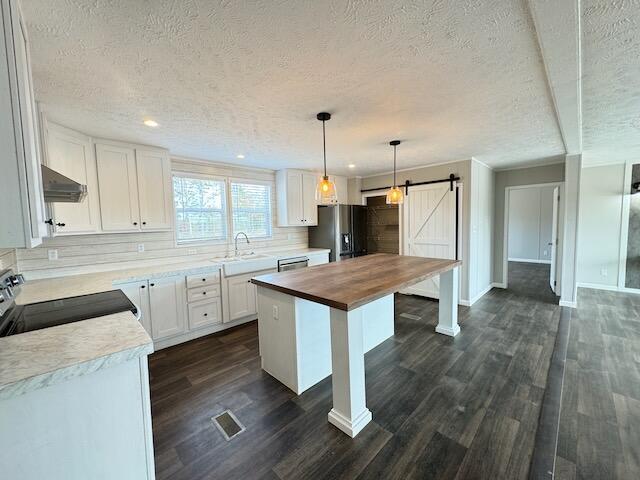 kitchen featuring a sink, wood counters, a barn door, a textured ceiling, and appliances with stainless steel finishes