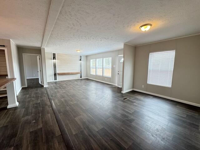 unfurnished living room with a textured ceiling, dark wood finished floors, and baseboards