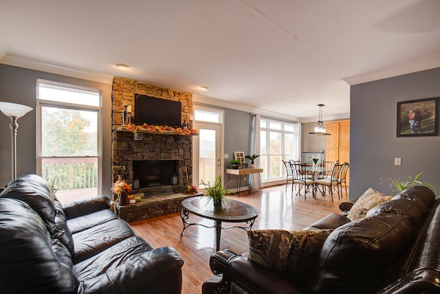 living room featuring light hardwood / wood-style floors, crown molding, and a stone fireplace