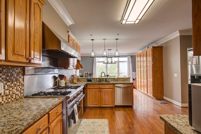 kitchen featuring decorative backsplash, light wood-type flooring, ornamental molding, decorative light fixtures, and stainless steel appliances