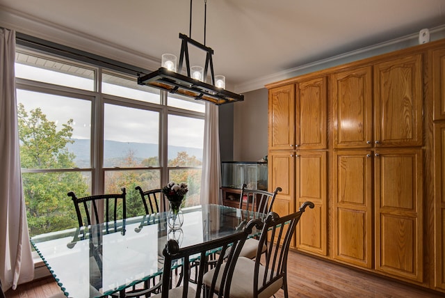 dining space featuring crown molding, a notable chandelier, and light hardwood / wood-style flooring