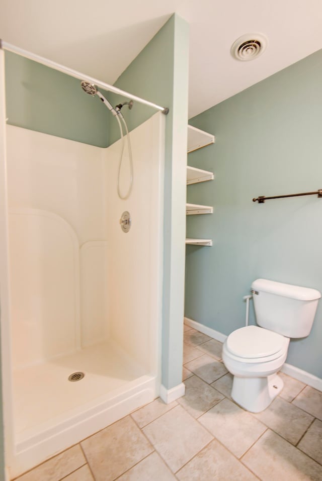 bathroom with toilet, walk in shower, and tile patterned flooring