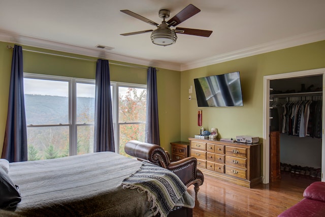 bedroom featuring ornamental molding, wood-type flooring, a closet, and ceiling fan