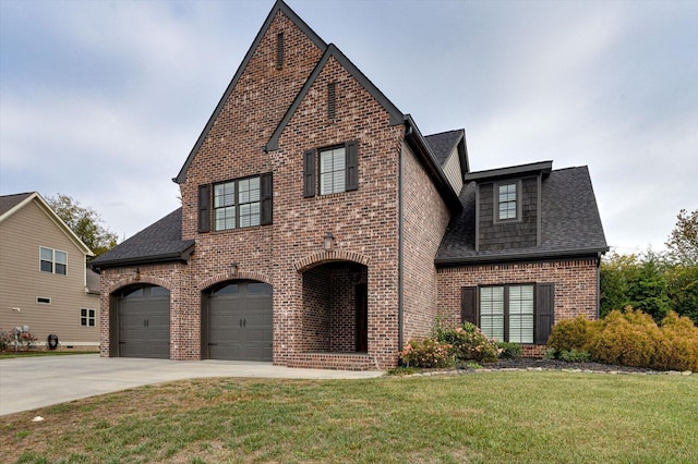 tudor-style house featuring a front yard and a garage