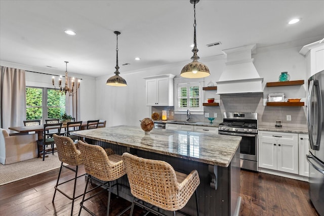 kitchen with a healthy amount of sunlight, appliances with stainless steel finishes, dark hardwood / wood-style floors, and white cabinets