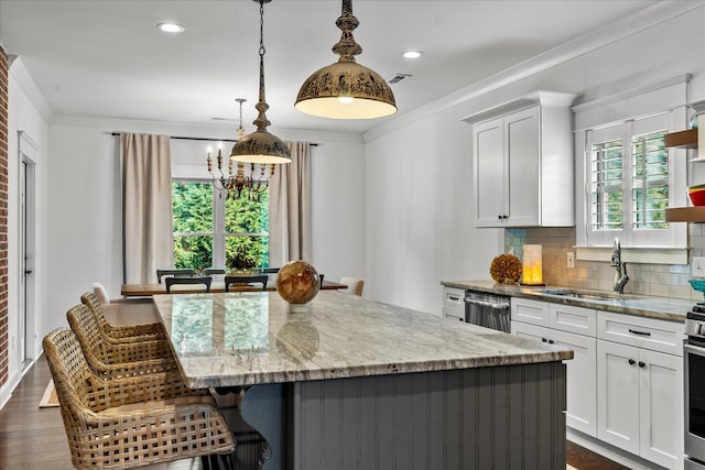 kitchen featuring white cabinetry, light stone countertops, hanging light fixtures, and a kitchen island