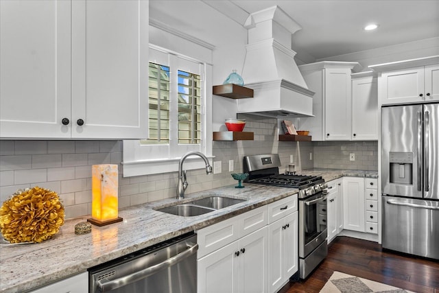 kitchen featuring premium range hood, white cabinets, stainless steel appliances, and sink