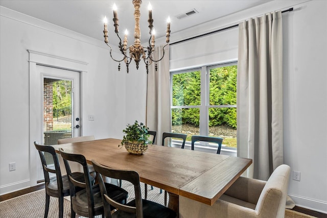 dining space with crown molding, hardwood / wood-style floors, a healthy amount of sunlight, and a chandelier