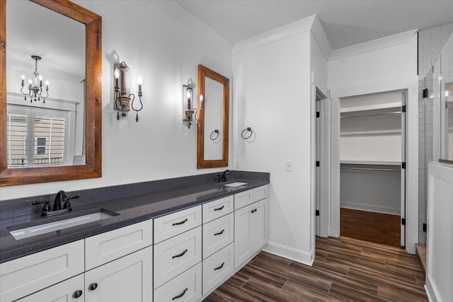 bathroom with vanity, a notable chandelier, ornamental molding, and hardwood / wood-style flooring