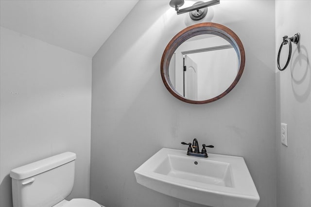 bathroom with toilet, lofted ceiling, and sink