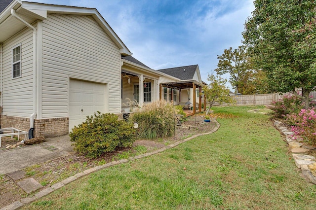 view of side of home with a garage, covered porch, and a lawn