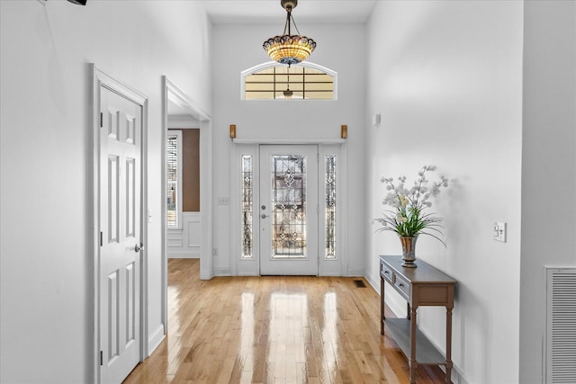 foyer entrance with a towering ceiling and light wood-type flooring