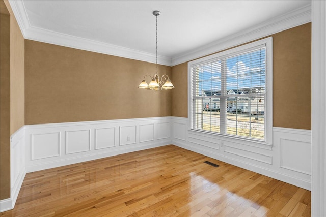 unfurnished room with an inviting chandelier, light hardwood / wood-style flooring, and ornamental molding