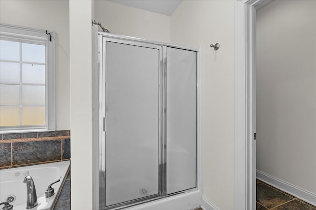 bathroom featuring plenty of natural light and separate shower and tub