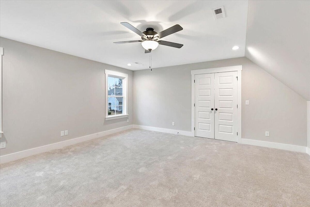 unfurnished bedroom featuring lofted ceiling, light colored carpet, a closet, and ceiling fan