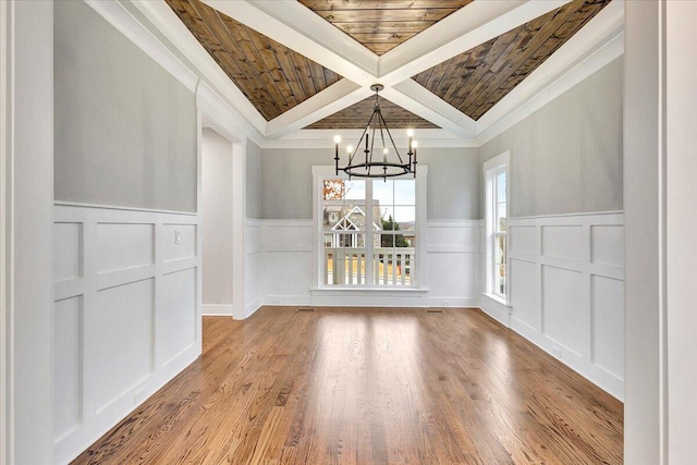 unfurnished dining area featuring wood ceiling, beam ceiling, an inviting chandelier, light hardwood / wood-style floors, and crown molding