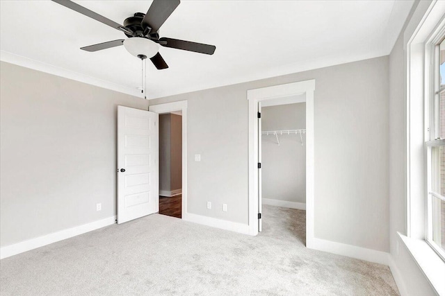 unfurnished bedroom with ceiling fan, baseboards, a closet, a spacious closet, and carpet flooring