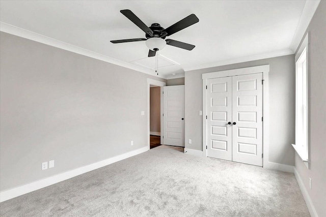 unfurnished bedroom featuring carpet, crown molding, a closet, and ceiling fan