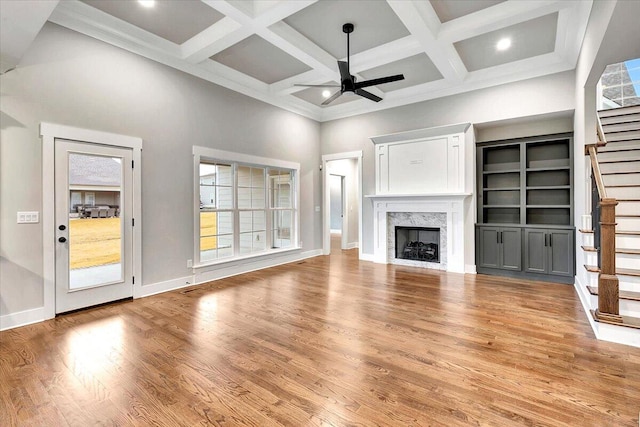 unfurnished living room with light hardwood / wood-style floors, coffered ceiling, beamed ceiling, and ceiling fan