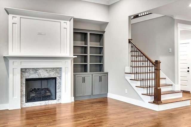 unfurnished living room with baseboards, wood finished floors, stairway, and a fireplace