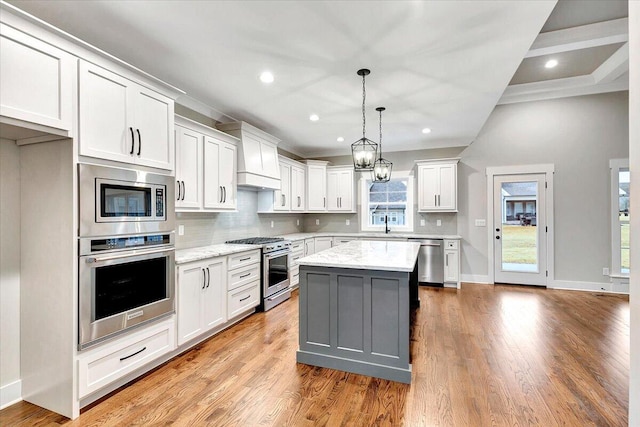 kitchen featuring appliances with stainless steel finishes, white cabinetry, a healthy amount of sunlight, and a center island