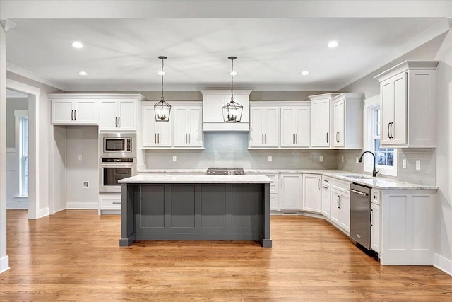 kitchen featuring a kitchen island, stainless steel appliances, sink, decorative light fixtures, and light hardwood / wood-style floors