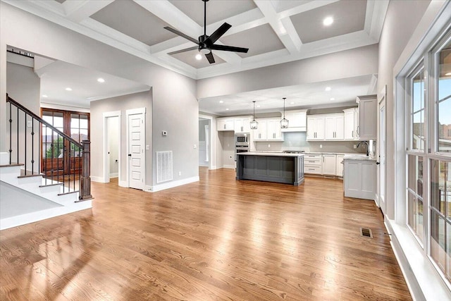 living room featuring sink, coffered ceiling, beamed ceiling, and light hardwood / wood-style flooring