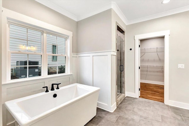 full bath with a freestanding tub, ornamental molding, a stall shower, and a spacious closet