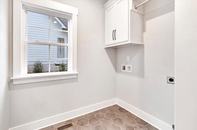 clothes washing area featuring cabinets, hookup for a washing machine, dark tile patterned floors, and electric dryer hookup