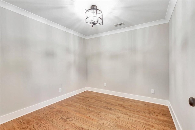 unfurnished room with crown molding, visible vents, an inviting chandelier, and light wood-style floors