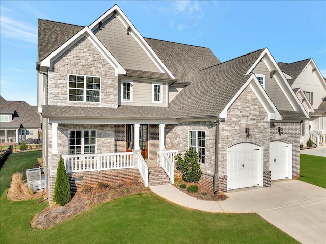 craftsman-style home featuring a front lawn, driveway, covered porch, and stone siding