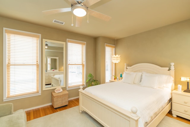 bedroom featuring ceiling fan, multiple windows, and light wood-type flooring