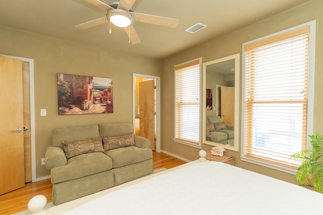 bedroom featuring multiple windows, hardwood / wood-style floors, and ceiling fan