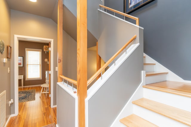 stairs featuring hardwood / wood-style flooring and vaulted ceiling