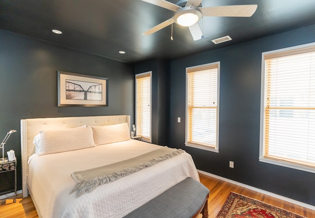 bedroom with light hardwood / wood-style floors, multiple windows, and ceiling fan