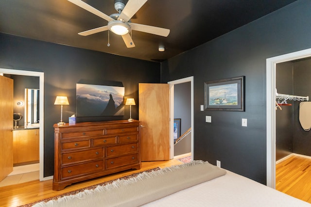 bedroom featuring a spacious closet, hardwood / wood-style floors, a closet, and ceiling fan