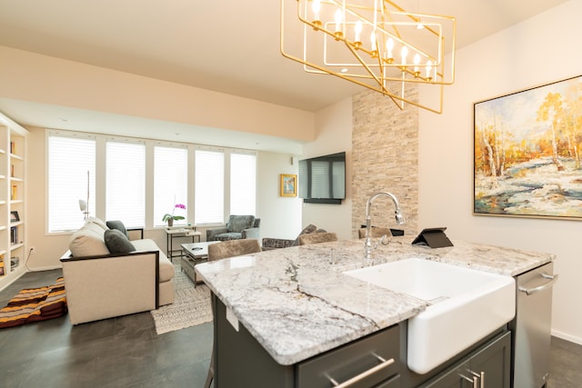 kitchen featuring an island with sink, sink, decorative light fixtures, a chandelier, and light stone counters