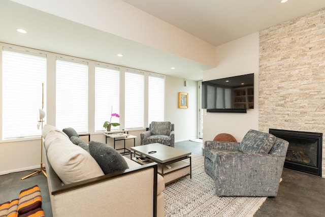 living room featuring a stone fireplace and concrete floors