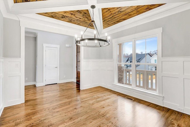 unfurnished dining area featuring wood ceiling, beamed ceiling, ornamental molding, light wood-type flooring, and a chandelier