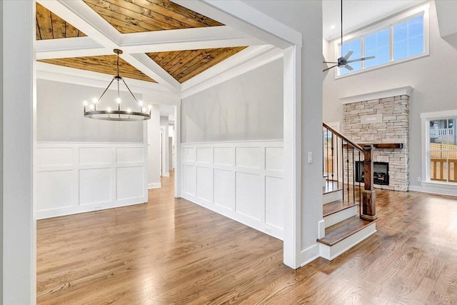 unfurnished dining area featuring a stone fireplace, light hardwood / wood-style flooring, wooden ceiling, and crown molding