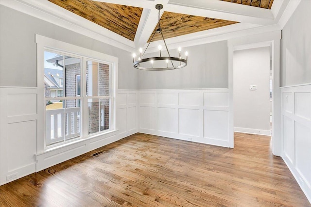 unfurnished dining area featuring wainscoting, a decorative wall, and a chandelier